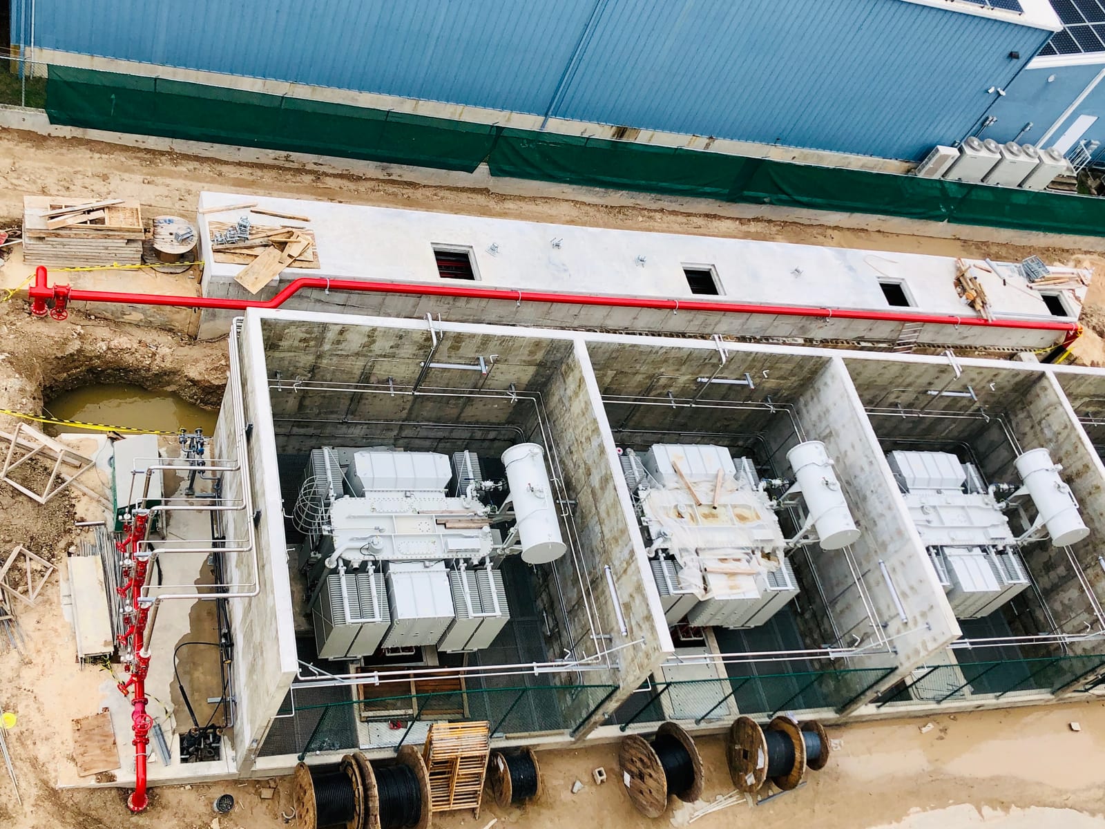 Red fire main running along the top of the transformer bays, seen from height