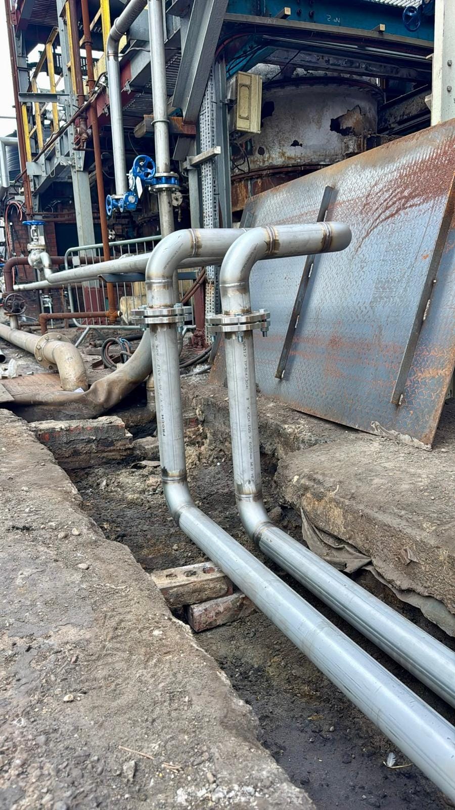 New pipework turning up out of the pit past a steel cover plate