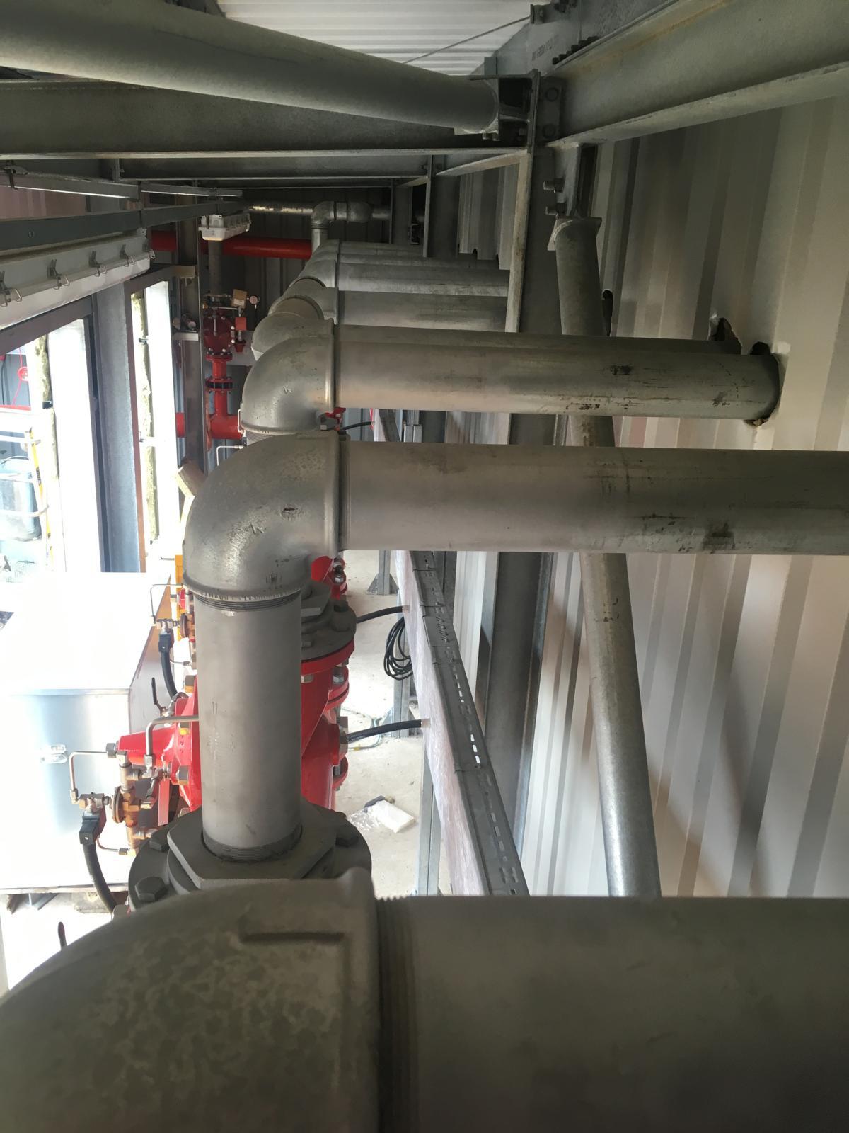 Galvanised process pipework alongside red fire mains