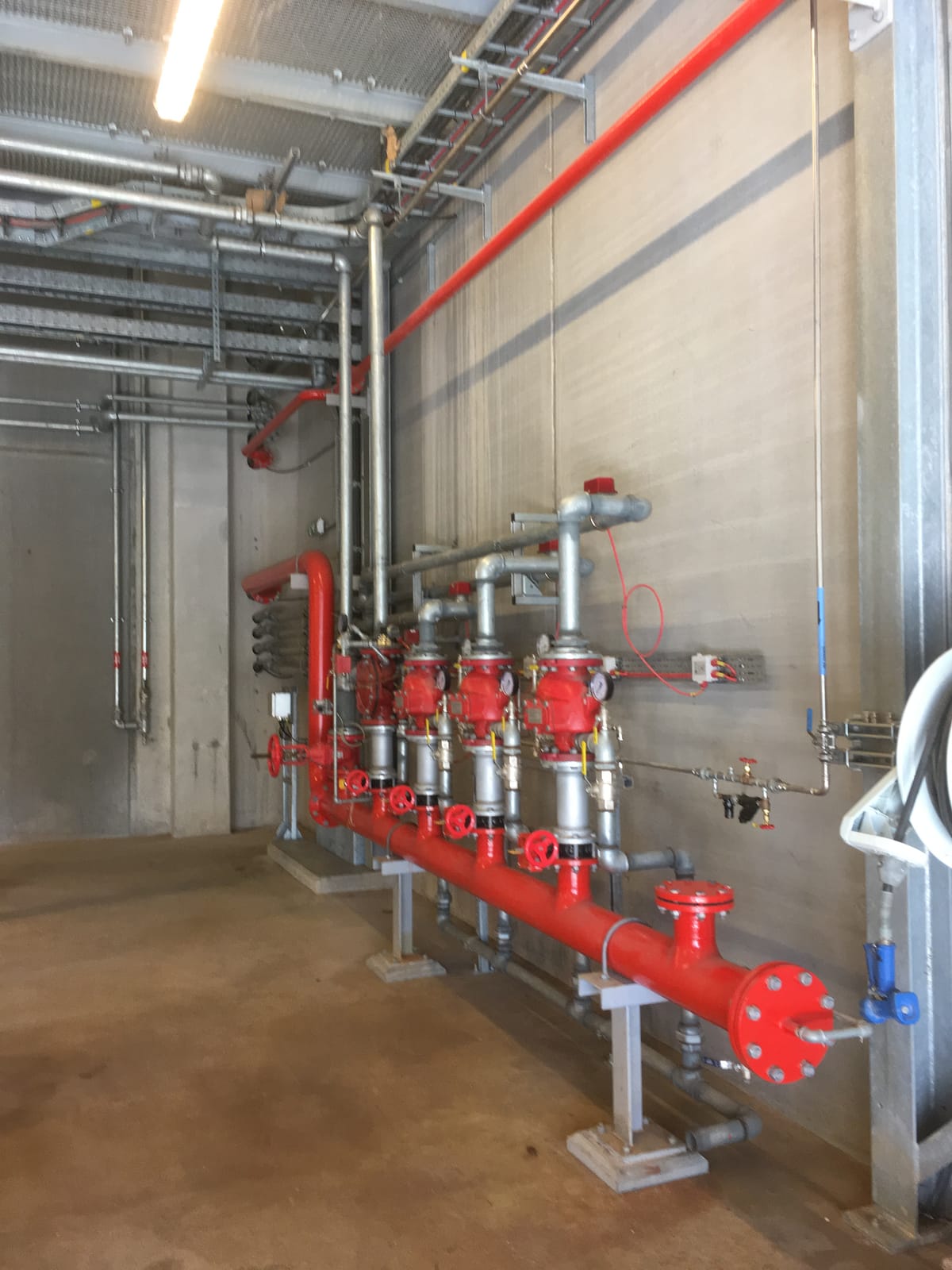 Red fire main and valve sets running along the plant room wall